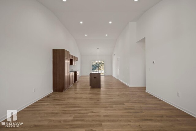 hall featuring high vaulted ceiling, dark hardwood / wood-style flooring, and an inviting chandelier