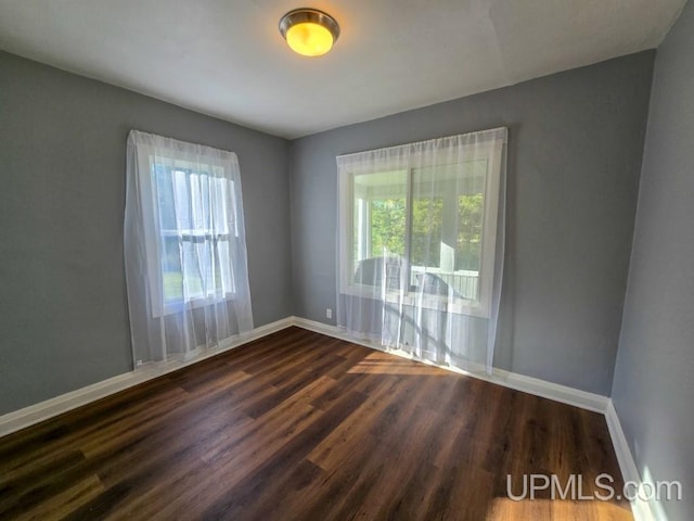 empty room with dark wood-type flooring and a healthy amount of sunlight