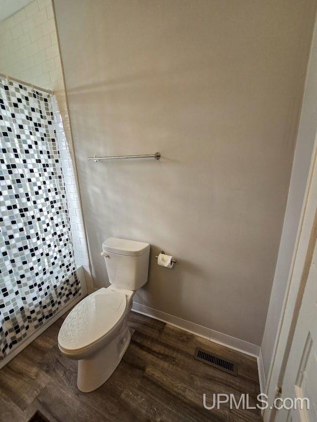 bathroom featuring wood-type flooring, a shower with curtain, and toilet