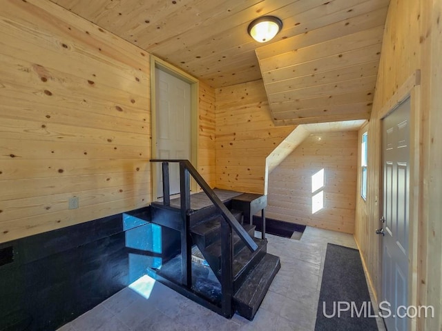 stairway featuring wooden ceiling, vaulted ceiling with skylight, and wood walls