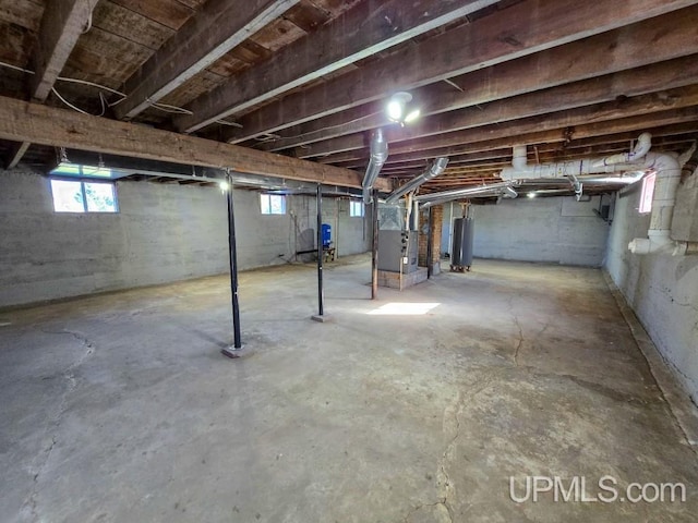 basement featuring gas water heater, a wealth of natural light, and heating unit