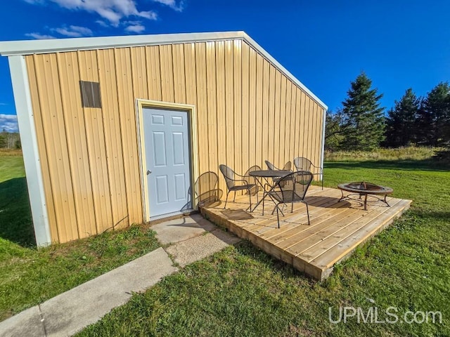 view of outbuilding featuring a fire pit and a lawn