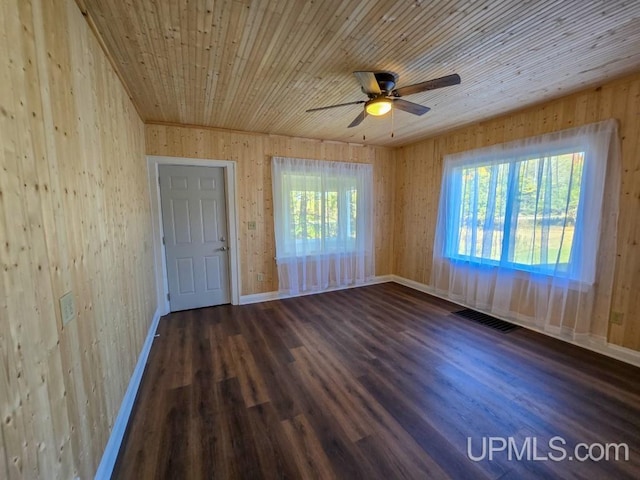 spare room with wood walls, ceiling fan, and dark wood-type flooring