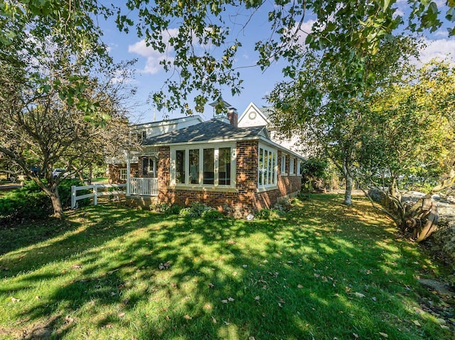 back of house featuring a lawn and a sunroom