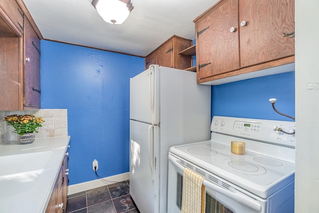 kitchen with dark tile patterned floors, sink, and white appliances