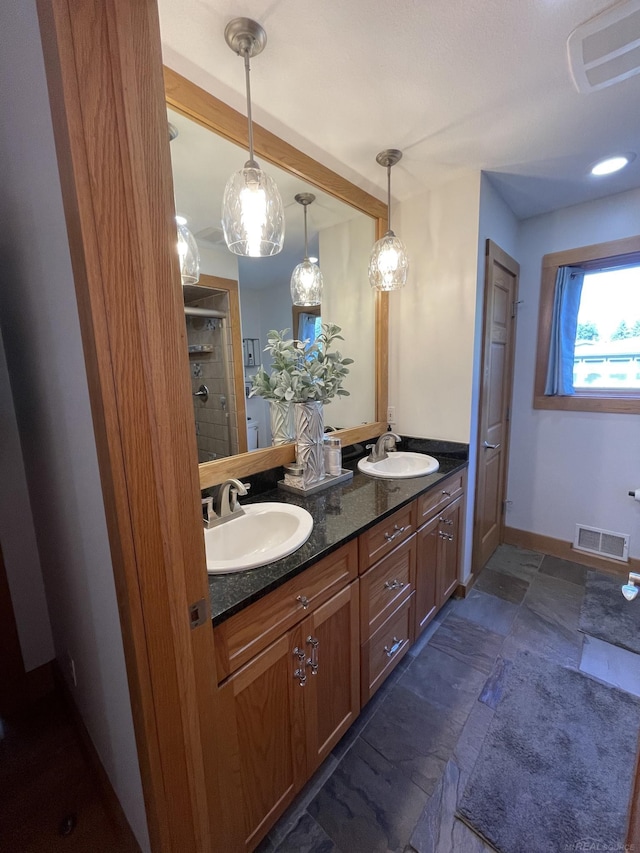 bathroom featuring a tile shower and vanity