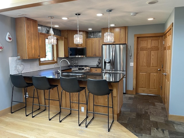 kitchen featuring pendant lighting, appliances with stainless steel finishes, tasteful backsplash, and a kitchen breakfast bar