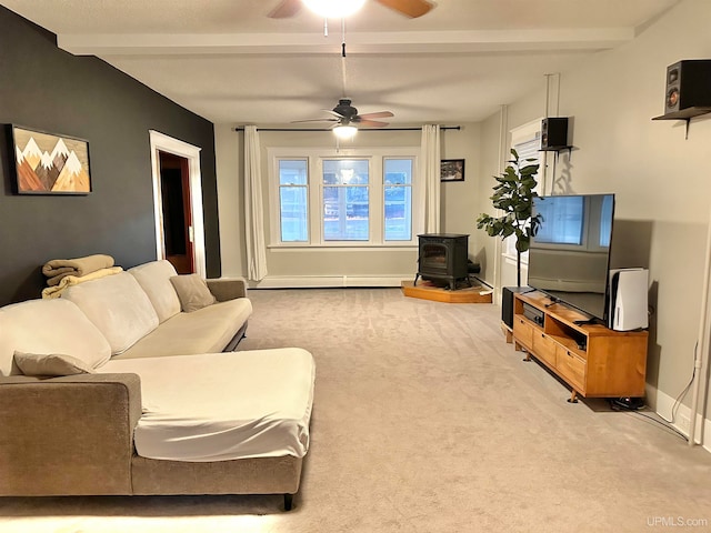 living room with a baseboard heating unit, beamed ceiling, a wood stove, light colored carpet, and ceiling fan