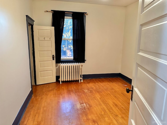 empty room featuring wood-type flooring and radiator