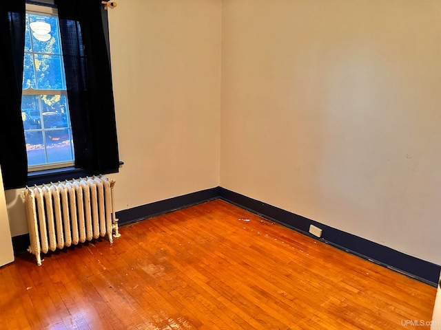 empty room featuring radiator and hardwood / wood-style floors