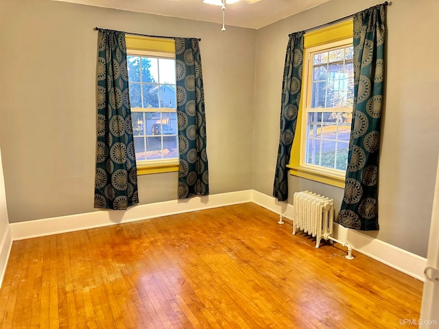 unfurnished room with radiator, ceiling fan, and hardwood / wood-style flooring