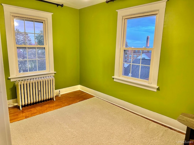 spare room featuring radiator heating unit and hardwood / wood-style flooring