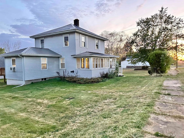 back house at dusk with cooling unit, a sunroom, and a yard