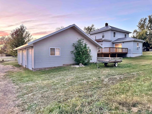 back house at dusk with a wooden deck and a yard