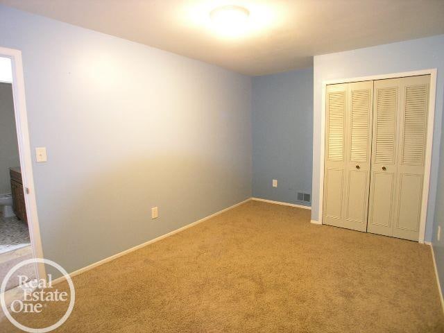 unfurnished bedroom with light carpet and a closet