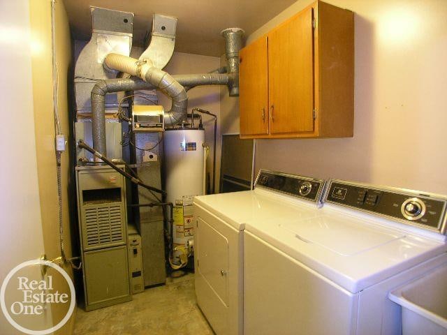 laundry room with water heater, sink, washer and dryer, and cabinets