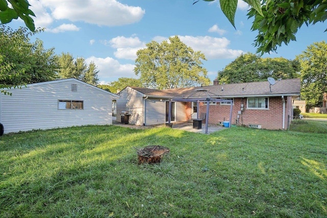 rear view of property with a fire pit, a lawn, and a patio