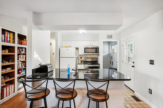 kitchen featuring light hardwood / wood-style floors, sink, white cabinets, a kitchen bar, and stainless steel appliances