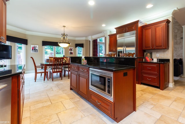 kitchen featuring pendant lighting, a center island, tasteful backsplash, built in appliances, and crown molding