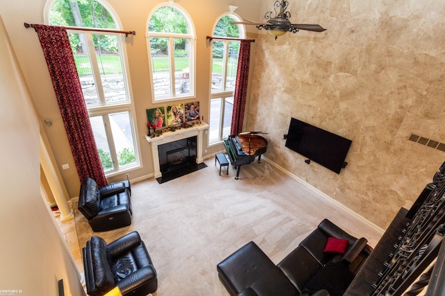 carpeted living room featuring a fireplace and ceiling fan