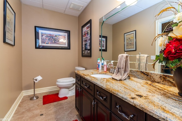 bathroom with vanity, a paneled ceiling, toilet, and tile patterned flooring