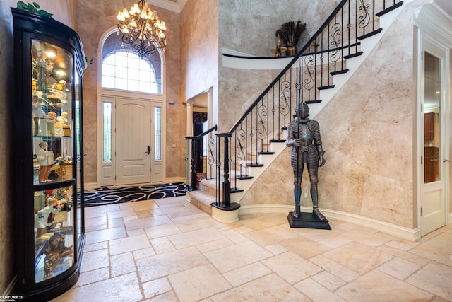 entrance foyer with ornamental molding, a towering ceiling, and a notable chandelier