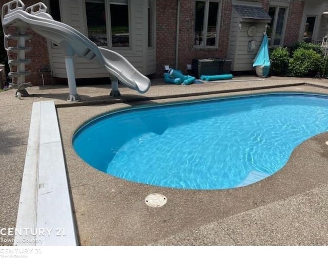 view of swimming pool featuring a water slide and a patio area