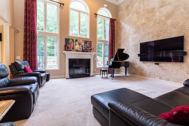 carpeted living room featuring ornamental molding, a towering ceiling, plenty of natural light, and ornate columns