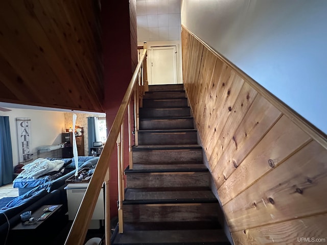 staircase featuring wooden walls