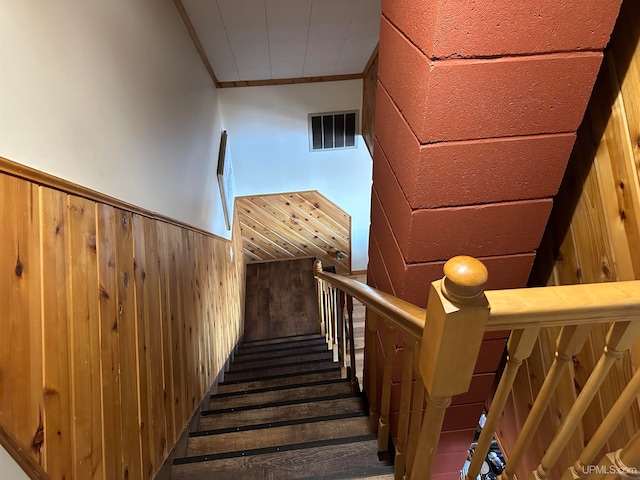 stairs featuring crown molding, wood walls, and hardwood / wood-style floors