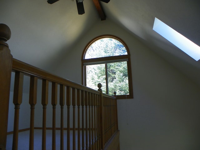 interior space featuring beam ceiling, ceiling fan, and a skylight