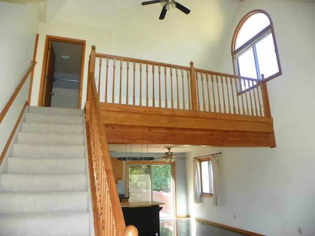 stairway featuring a towering ceiling and ceiling fan