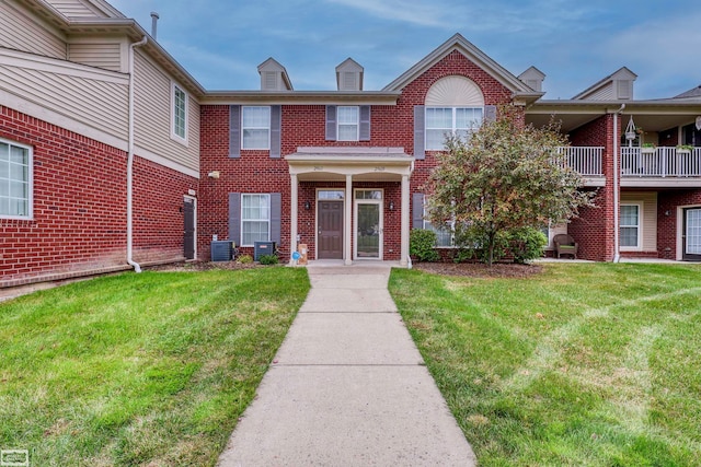 view of front of home featuring a balcony, central AC, and a front yard