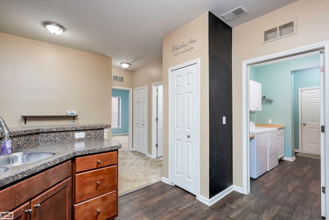 kitchen featuring washer and dryer, dark wood-type flooring, and sink