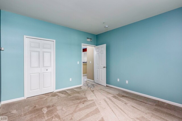 unfurnished bedroom with light carpet and a closet