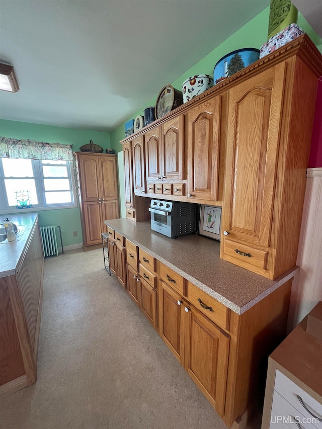 kitchen featuring light colored carpet and radiator heating unit