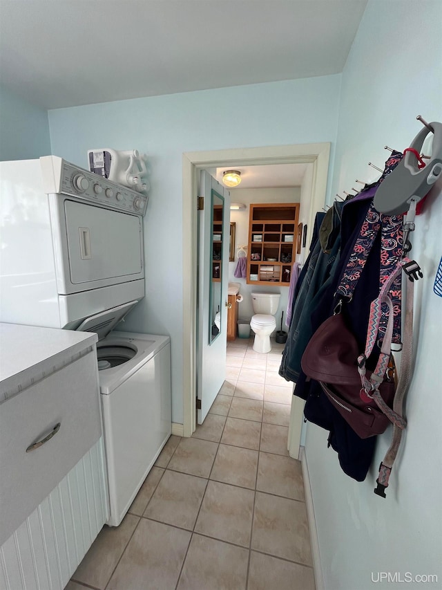 laundry room featuring light tile patterned flooring and stacked washer / dryer