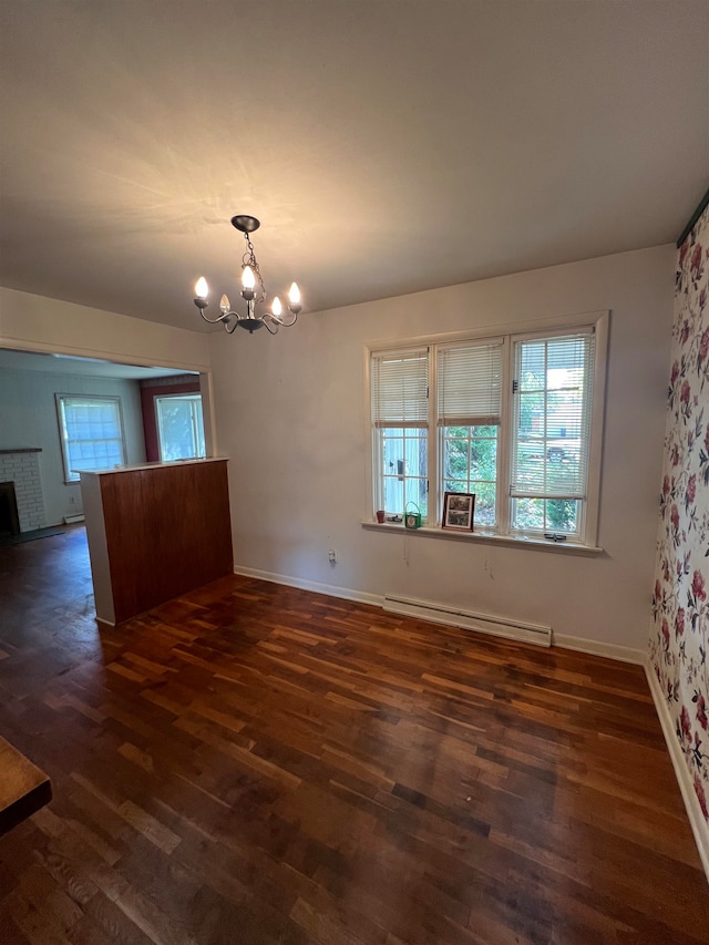 unfurnished dining area with a brick fireplace, a chandelier, baseboard heating, and dark hardwood / wood-style floors