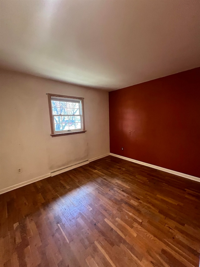 spare room with a baseboard radiator and dark hardwood / wood-style floors