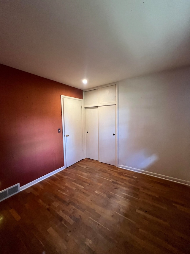 unfurnished bedroom with a closet and dark hardwood / wood-style flooring