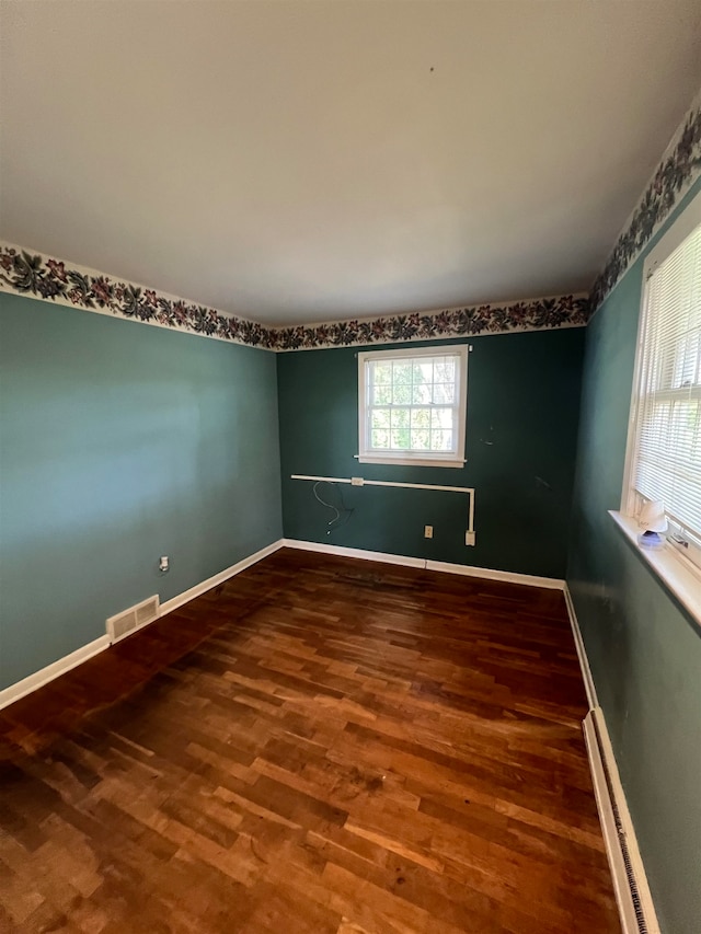 unfurnished room with wood-type flooring and baseboard heating