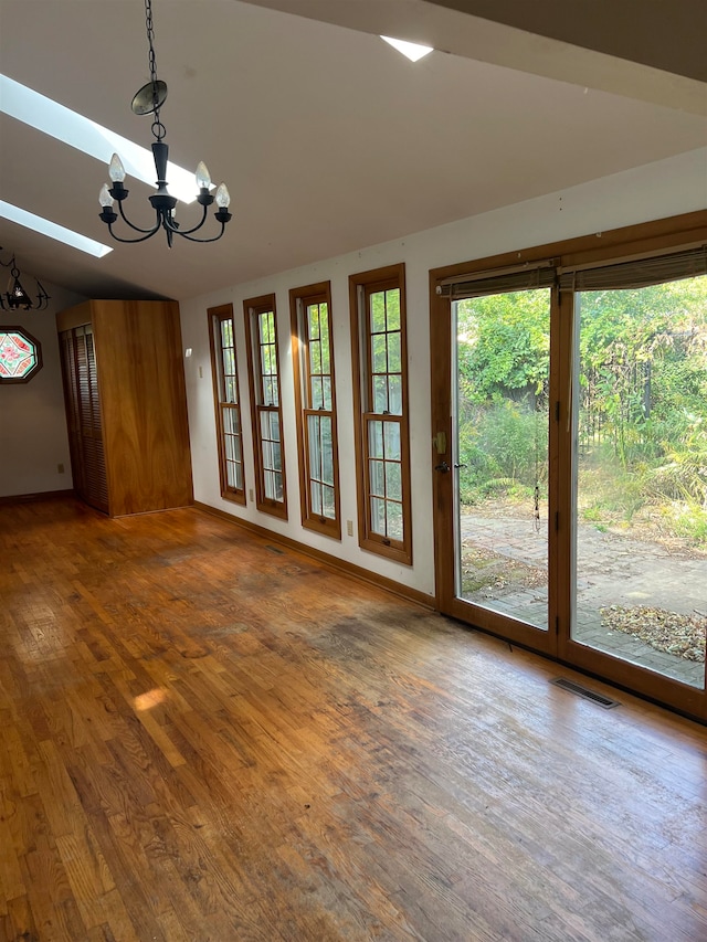 interior space featuring vaulted ceiling with skylight, dark hardwood / wood-style floors, and a notable chandelier