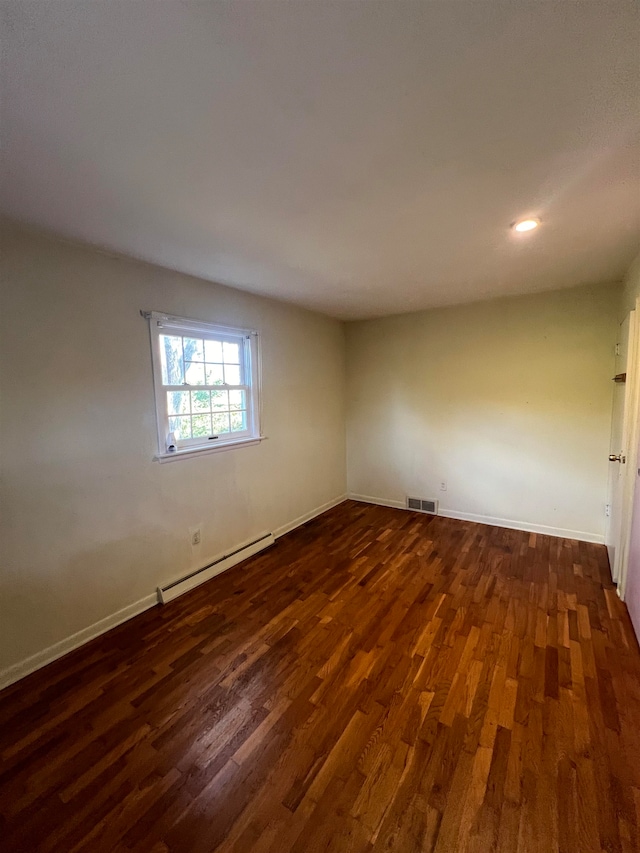 spare room featuring a baseboard radiator and dark hardwood / wood-style floors