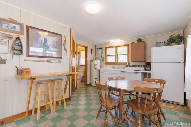 dining room featuring electric water heater, wooden walls, and sink