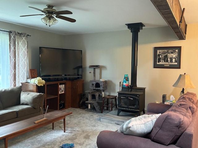 living room with light carpet, a wood stove, and ceiling fan