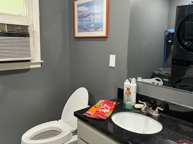 bathroom with vanity, stacked washer / drying machine, and toilet