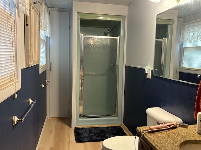 bathroom featuring vanity, toilet, wood-type flooring, and a shower with shower door