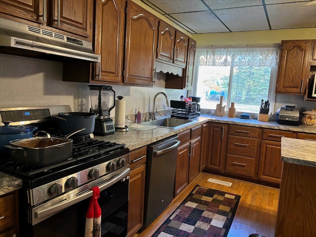 kitchen featuring light stone countertops, sink, a drop ceiling, light hardwood / wood-style floors, and stainless steel appliances