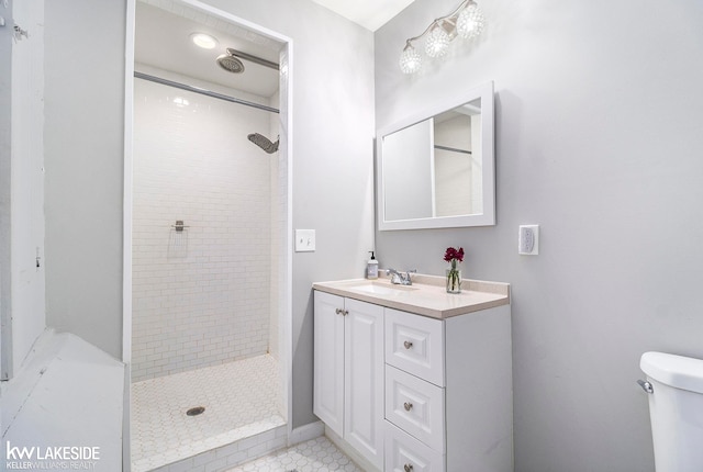 bathroom featuring vanity, toilet, a tile shower, and tile patterned floors