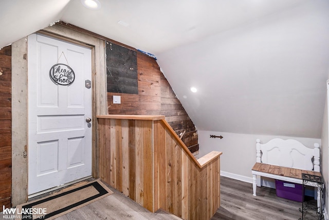 interior space with wood walls, wood-type flooring, and vaulted ceiling